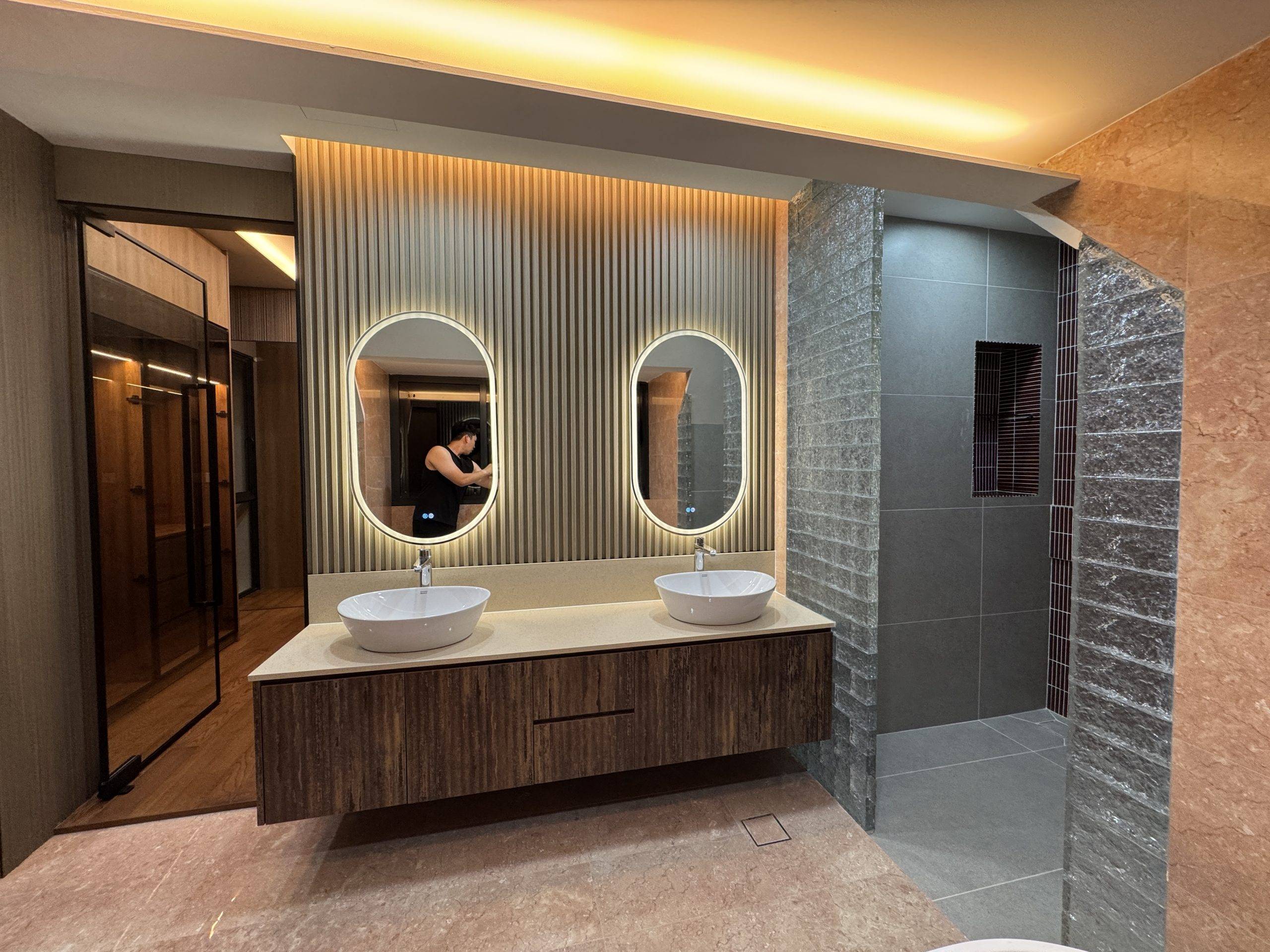 Modern residential bathroom renovation with two oval mirrors, elegant lighting, and twin wash basins